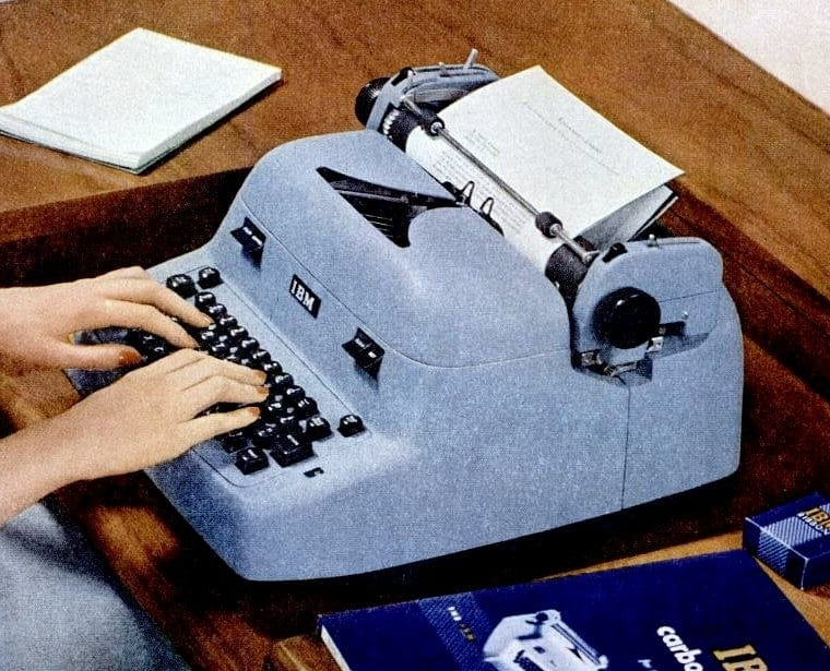Typewriter on a desk with someone typing on it